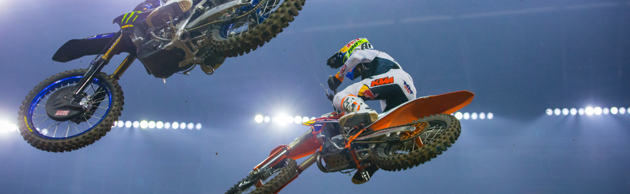 Motorcyclists performing tricks over camera
